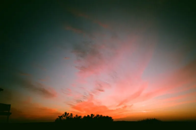 Pink and orange clouds over a dark horizon at dusk