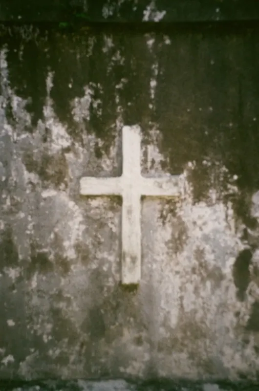 A white cross set into a stained concrete wall