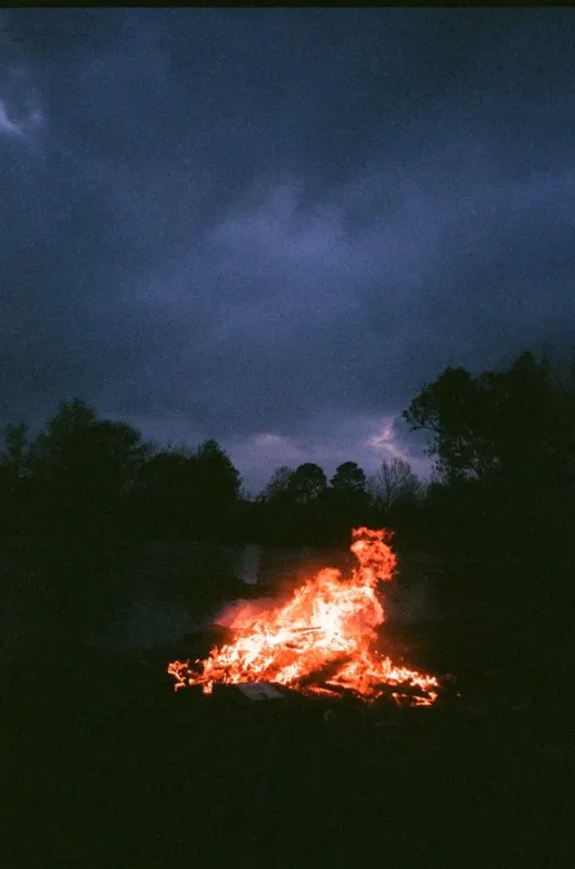 A bonfire burning under a dark blue evening sky